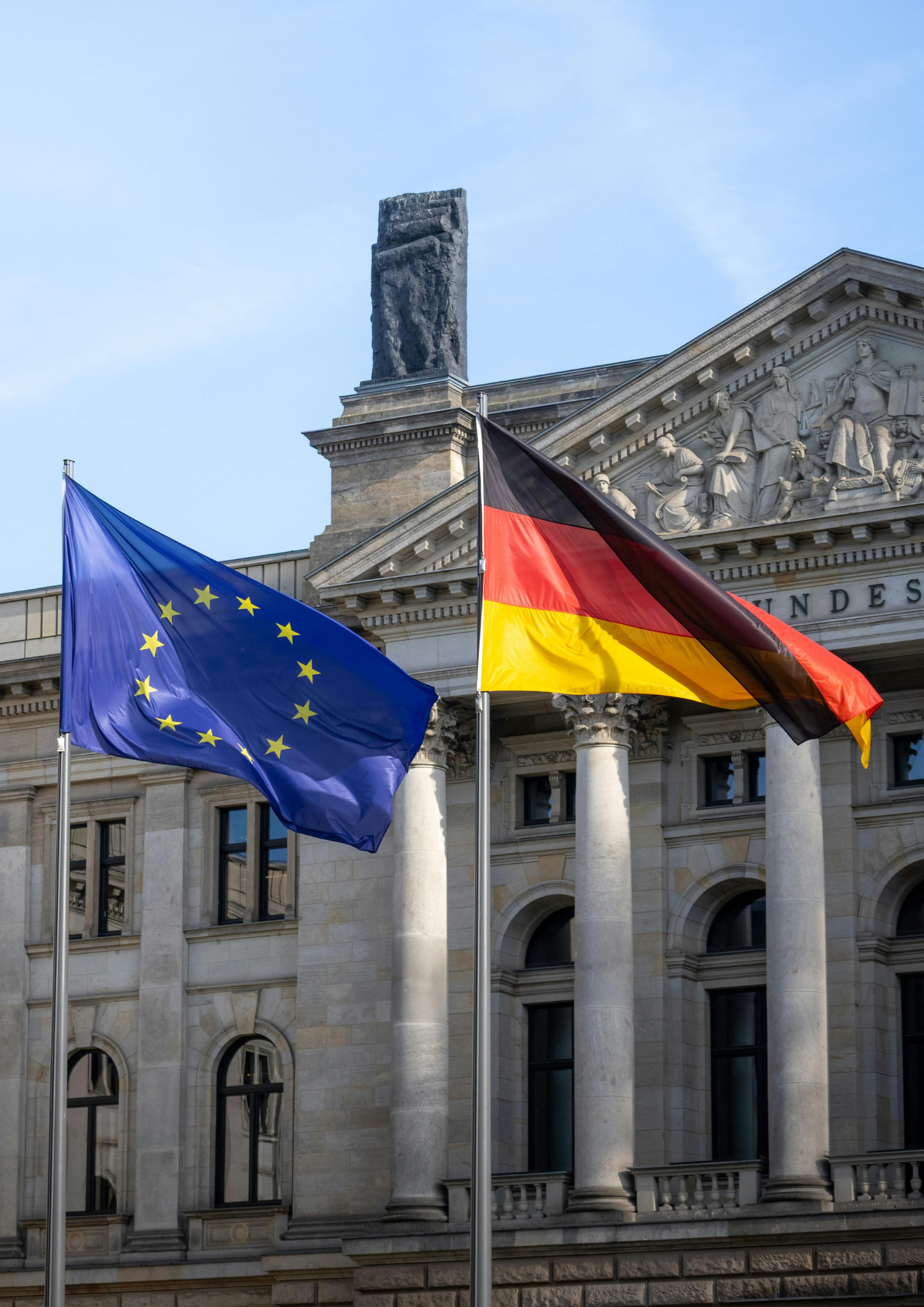 Flaginiemiecka oraz unii europejskiej, powiewające na tle historycznego budynku.