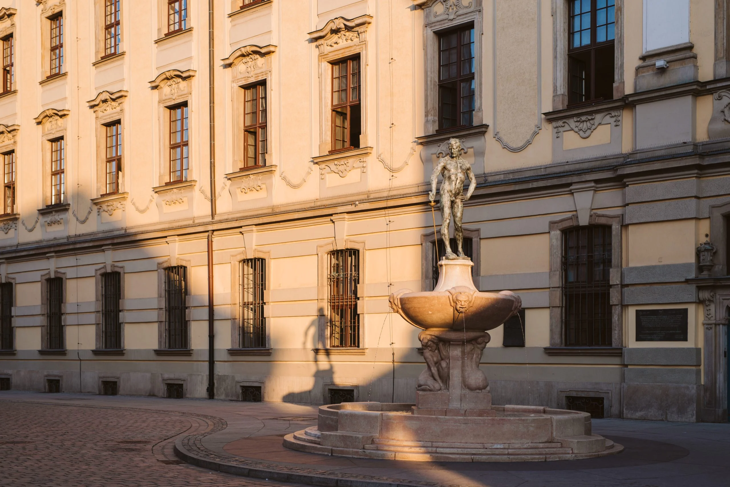 Widok na fontannę z szermierzem przed budynkiem gmachu głównego Uniwersytetu Wrocławskiego.
